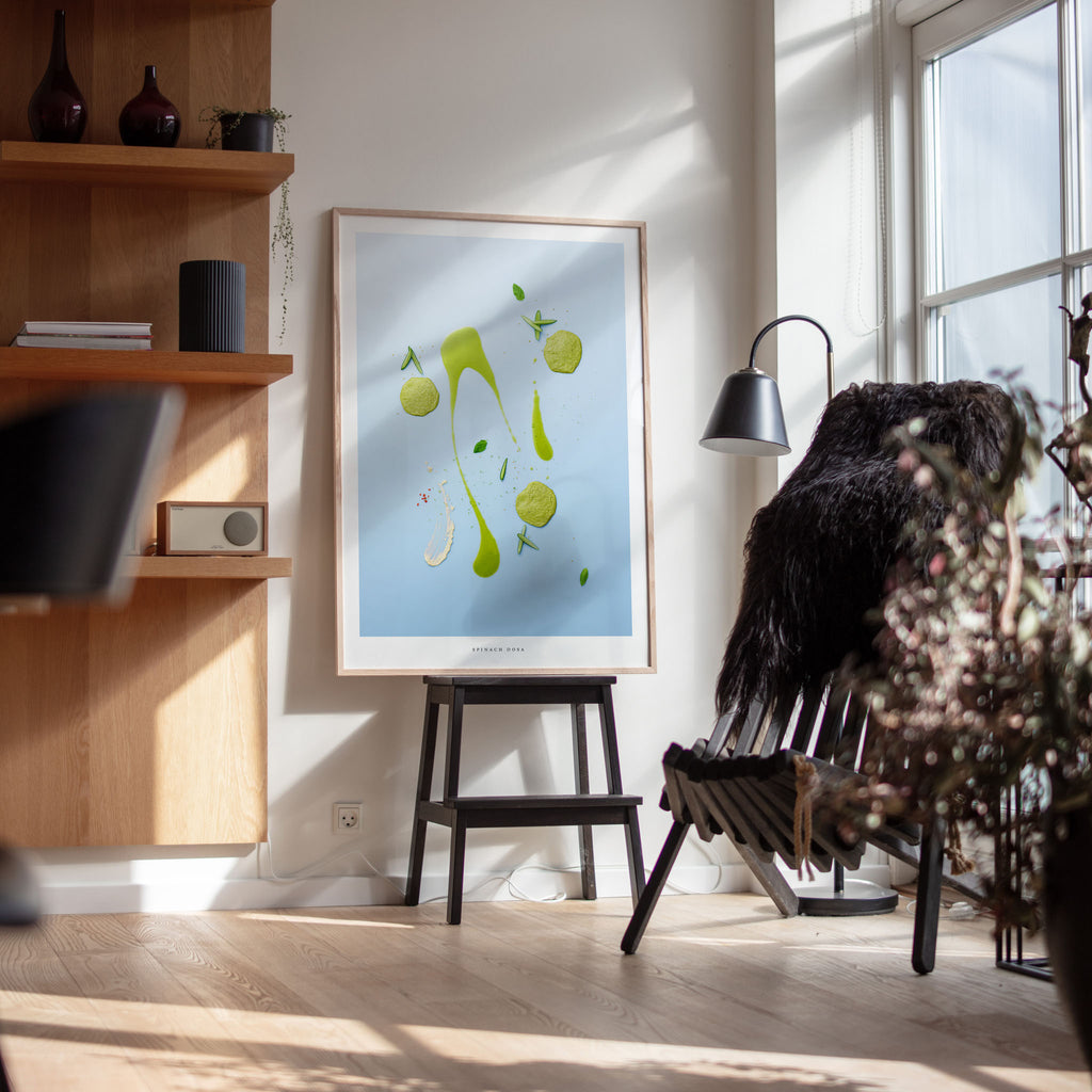 Spinach Dosa art print on easel in minimalist interior with wooden shelf