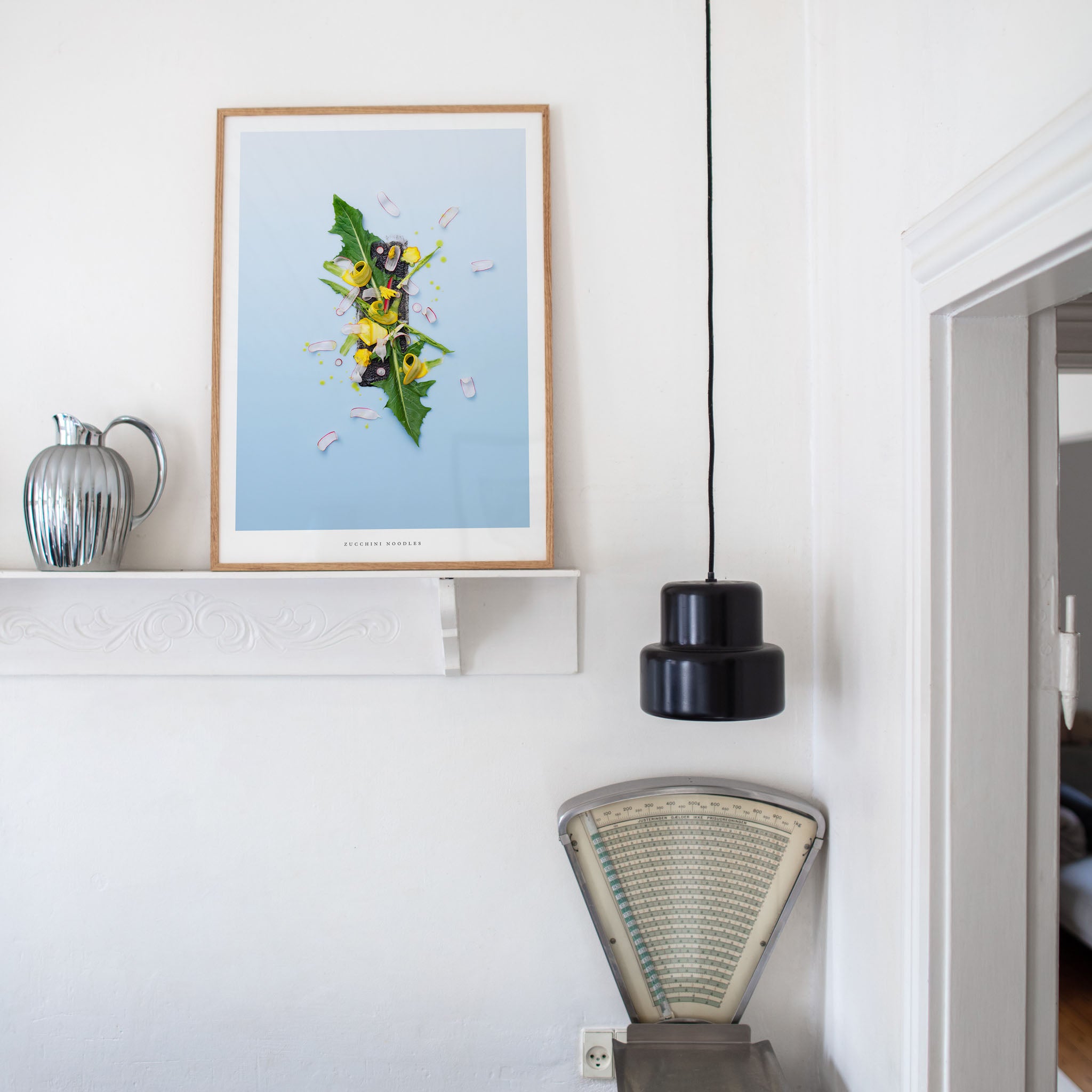 Zucchini Noodles botanical art print on a wall with a lamp and decorative items in a room.