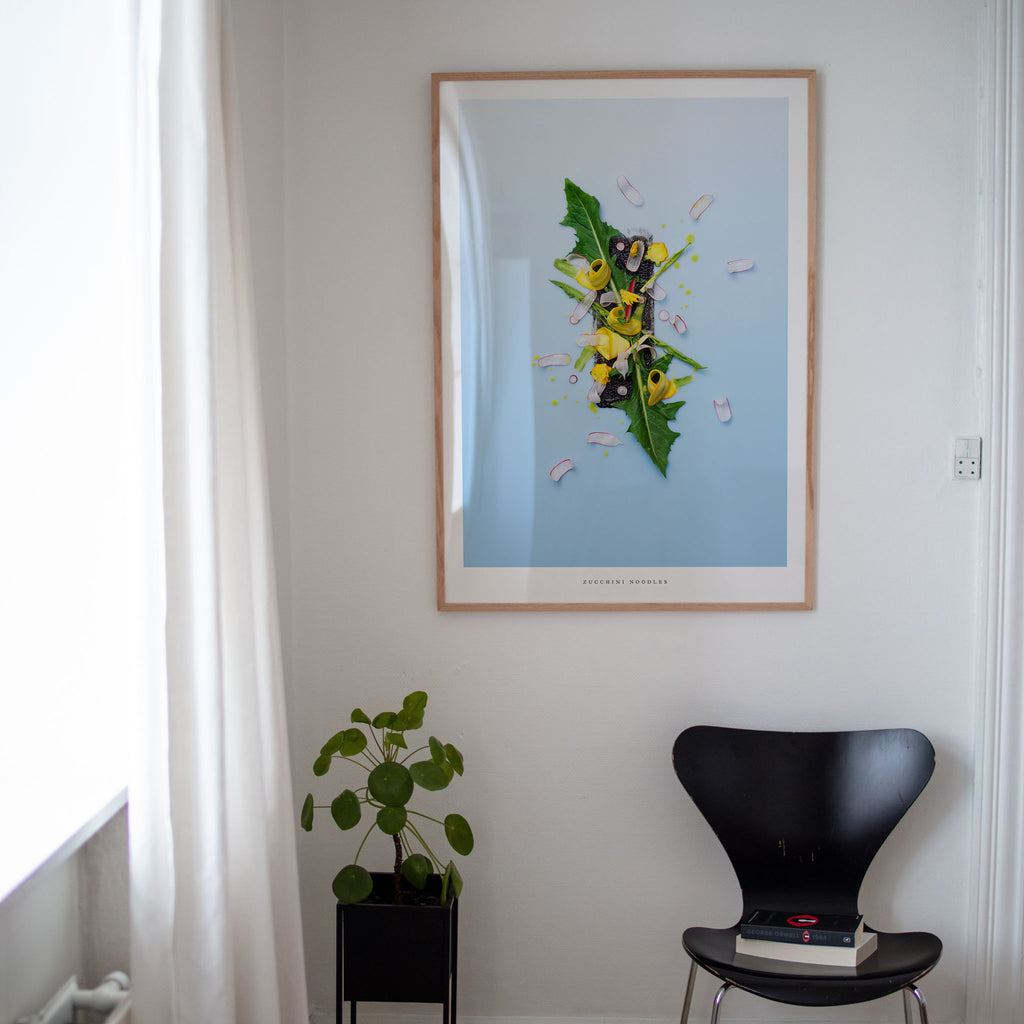 Zucchini Noodles art print on white wall with plant and black chair